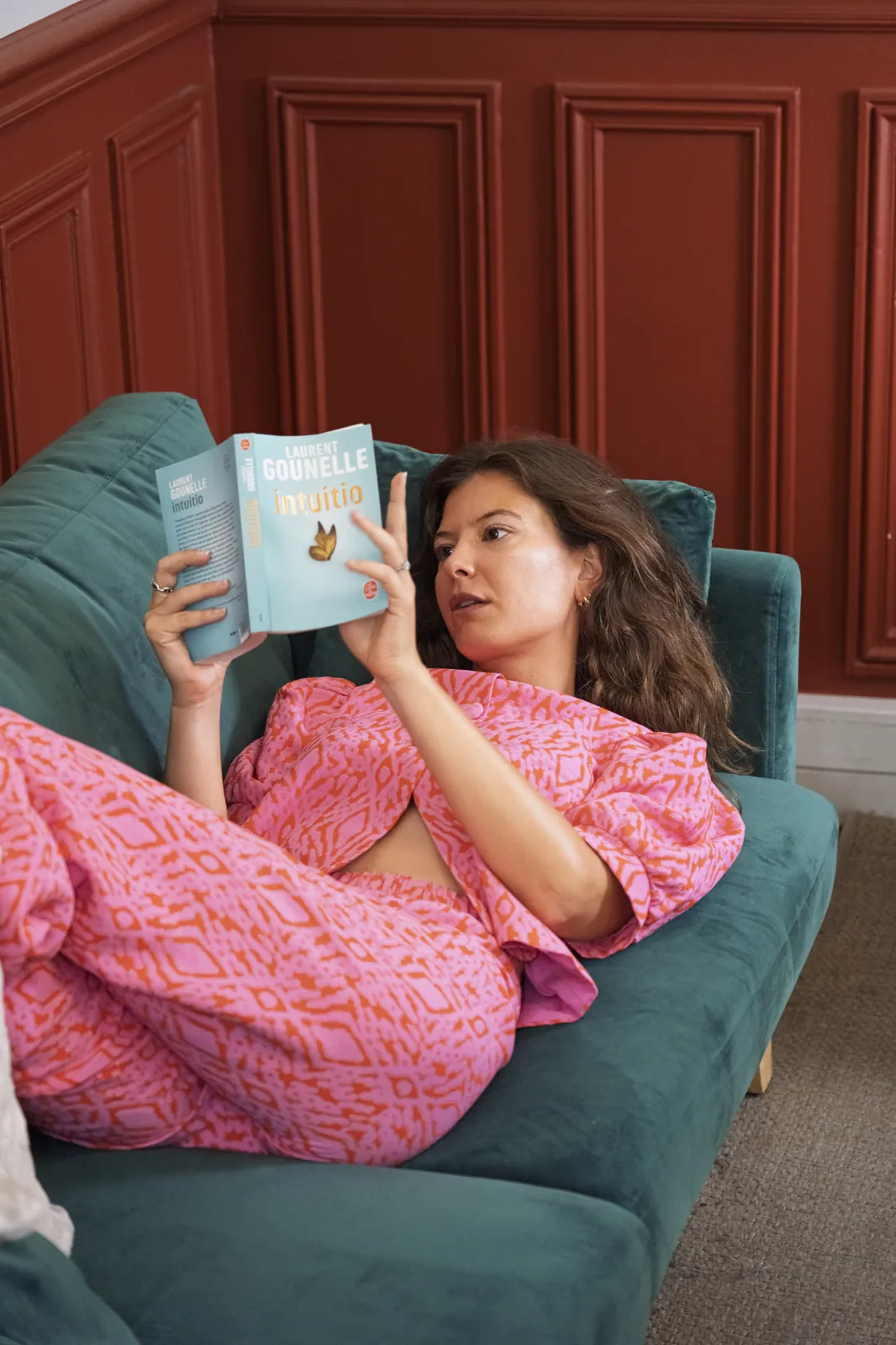 Lecture allongée sur le canapé vert, ensemble rose à motifs, séance portrait à Paris